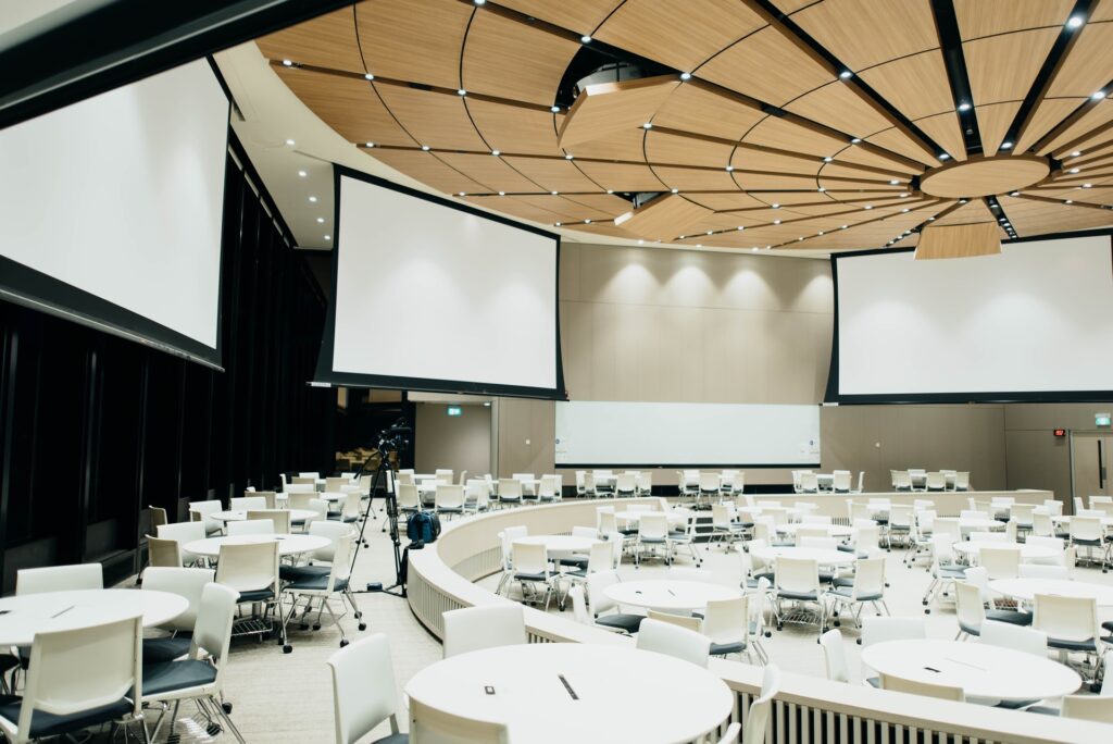 Empty corporate event room with projector screens and tables.