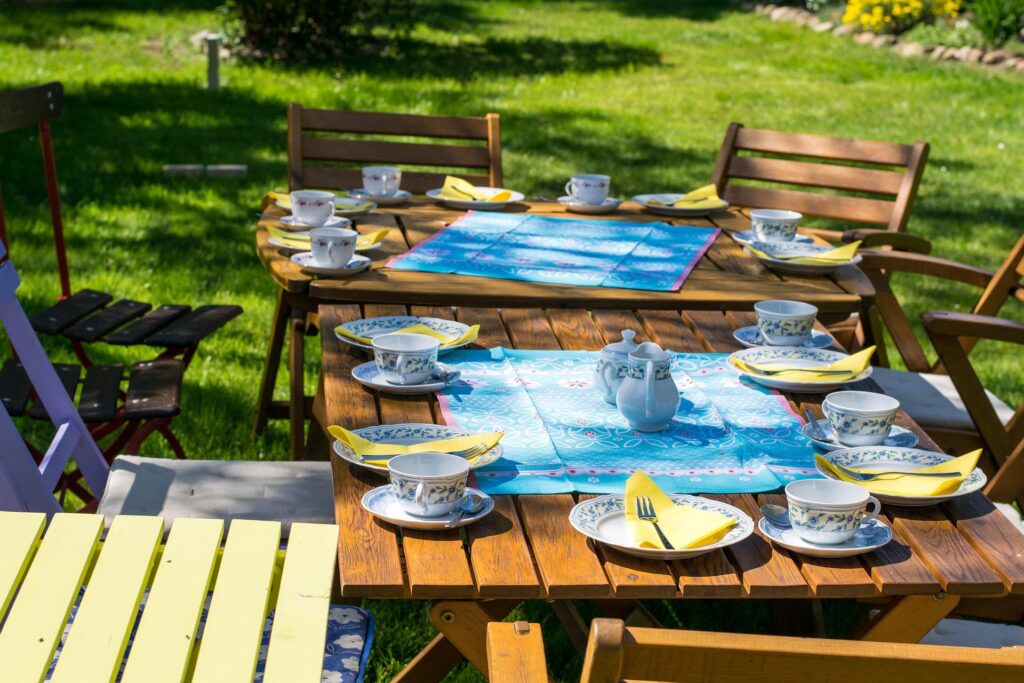 Wooden tables and chairs set up in a backyard.