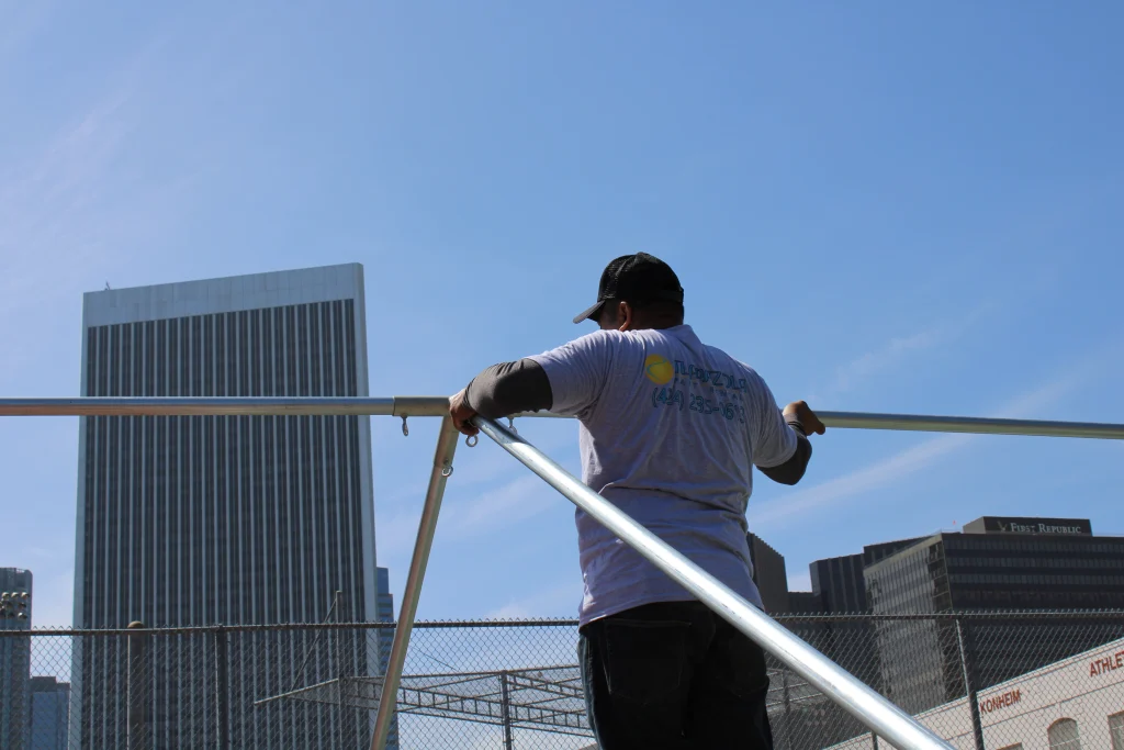 Team member assembling 20' by 20' tent with Los Angeles skyline in background for LA Student Run Marathon setup