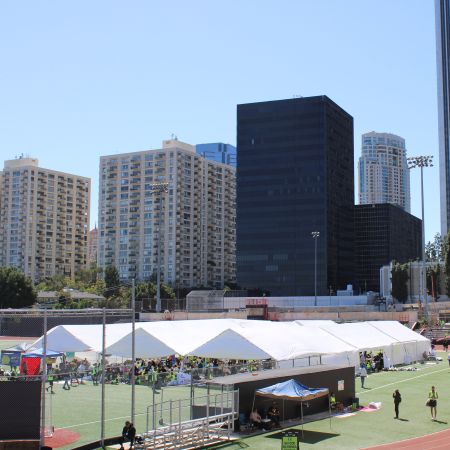 Top view of three 120ft by 30ft tents set up on a grassy field for runners to rest, with the LA skyscrapers in the background.