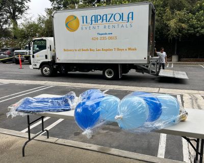 Tlapazola Event Rentals truck delivering party equipment including plastic folding tables and blue balloons for event setup in Los Angeles.