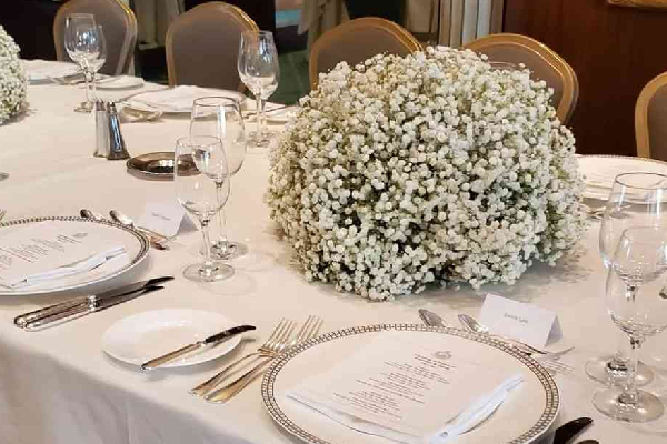 Elegant event table setup with white floral centerpiece, silver flatware, and custom menus—ideal for party event equipment rentals and delivery in Los Angeles.